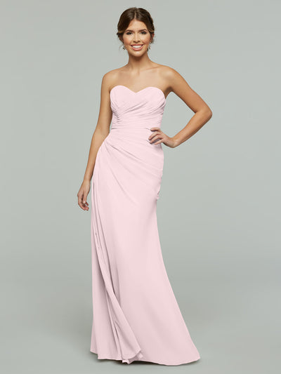A woman poses with one hand on her hip in Avery Austin’s 80028, a strapless, floor-length chiffon dress with a sweetheart neckline and ruched details, set against a plain grey background.