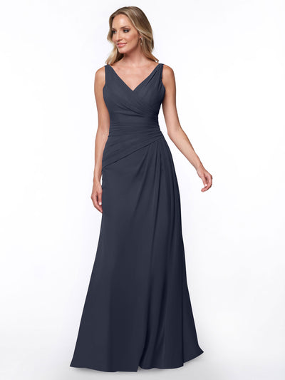 A woman models Avery Austin’s 80030: a sleeveless, floor-length dark blue sheath dress with a V-neckline and ruched bodice, standing before a plain white background.