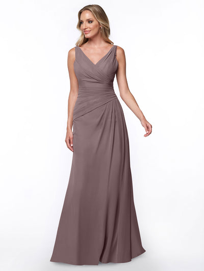 A woman wears Avery Austin style 80030, a long mauve sheath dress with a V-neck, sleeveless design, and gathered ruched bodice detail, standing against a plain white background.
