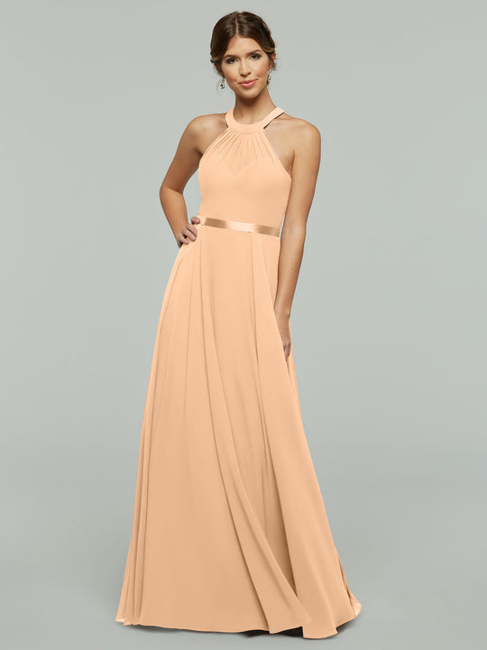 A woman wears the Avery Austin 80038 A-Line chiffon dress in blush, with a halter neckline and fitted waist, standing against a light gray background. She smiles with her hair in a loose updo.