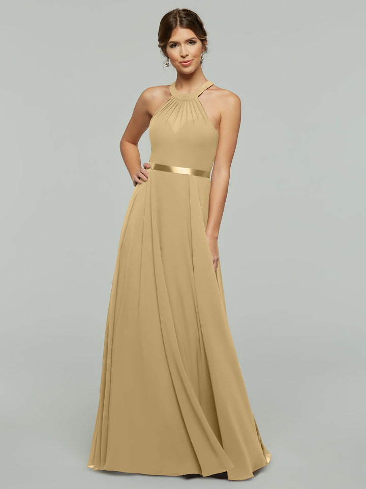 A model poses in Avery Austin’s 80038, a sleeveless champagne A-line chiffon gown with a halter neckline, satin waistband, and softly pleated skirt, set against a plain light gray background.