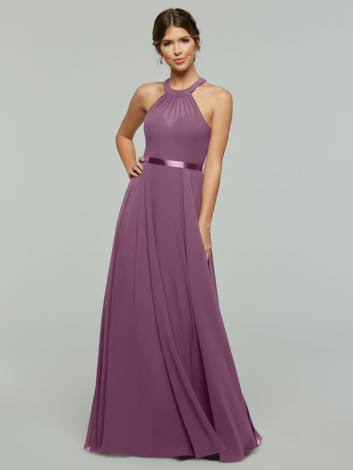 A woman in a long wisteria-colored halter dress poses against a light gray background.
