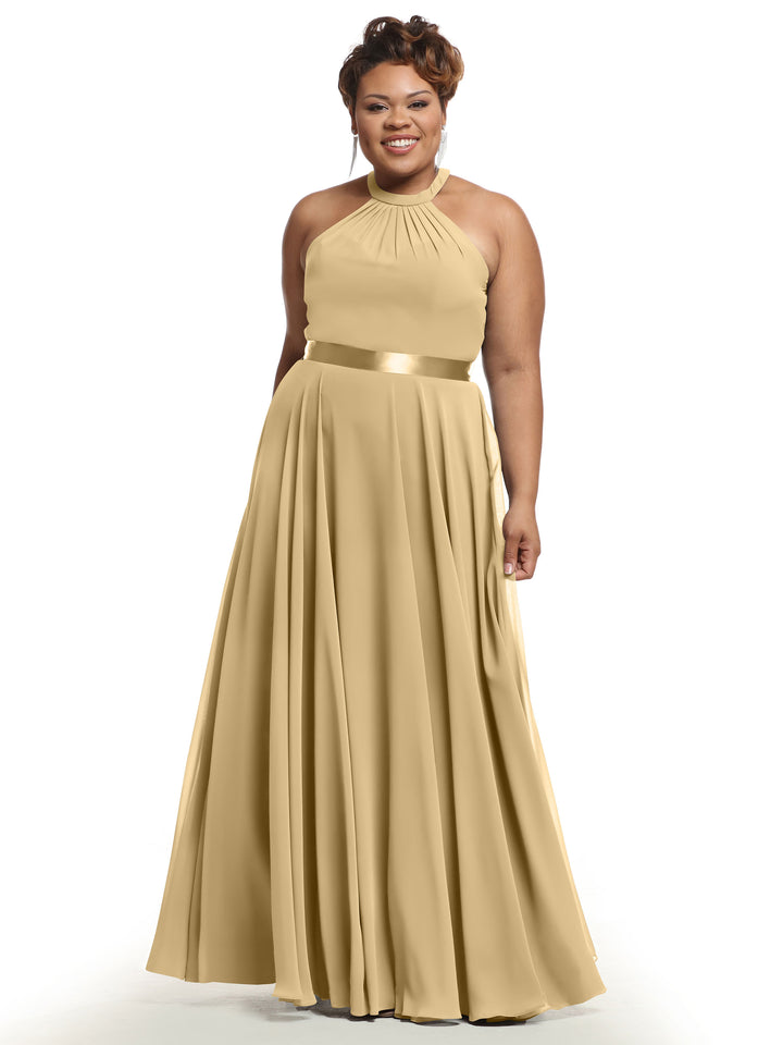 A woman smiles against a plain white background wearing Avery Austin 80038, a long sleeveless champagne A-line chiffon dress with a halter neckline and shiny belt.