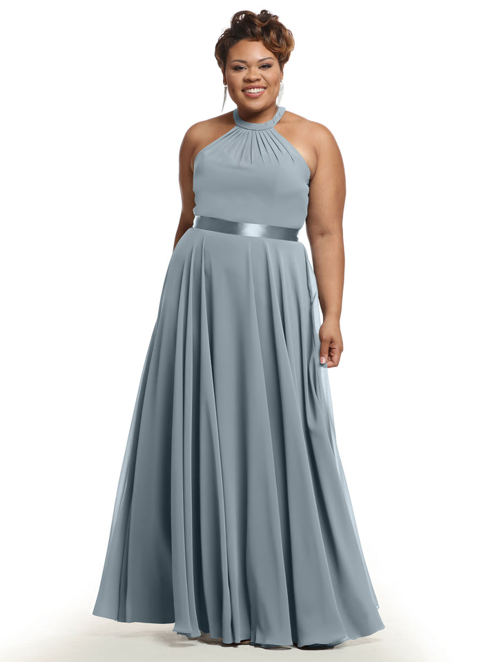 A woman smiles against a white background wearing Avery Austin 80038—a light blue, floor-length A-line chiffon dress with a halter neckline, pleated skirt, and satin waistband.