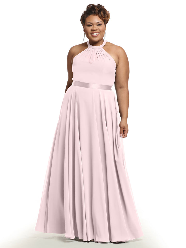 A woman smiles against a white background wearing Avery Austin’s TH-80038 dress in Rose Petal—a blush pink A-line chiffon gown with a halter neckline, fitted satin waistband, and flowing, floor-length skirt.