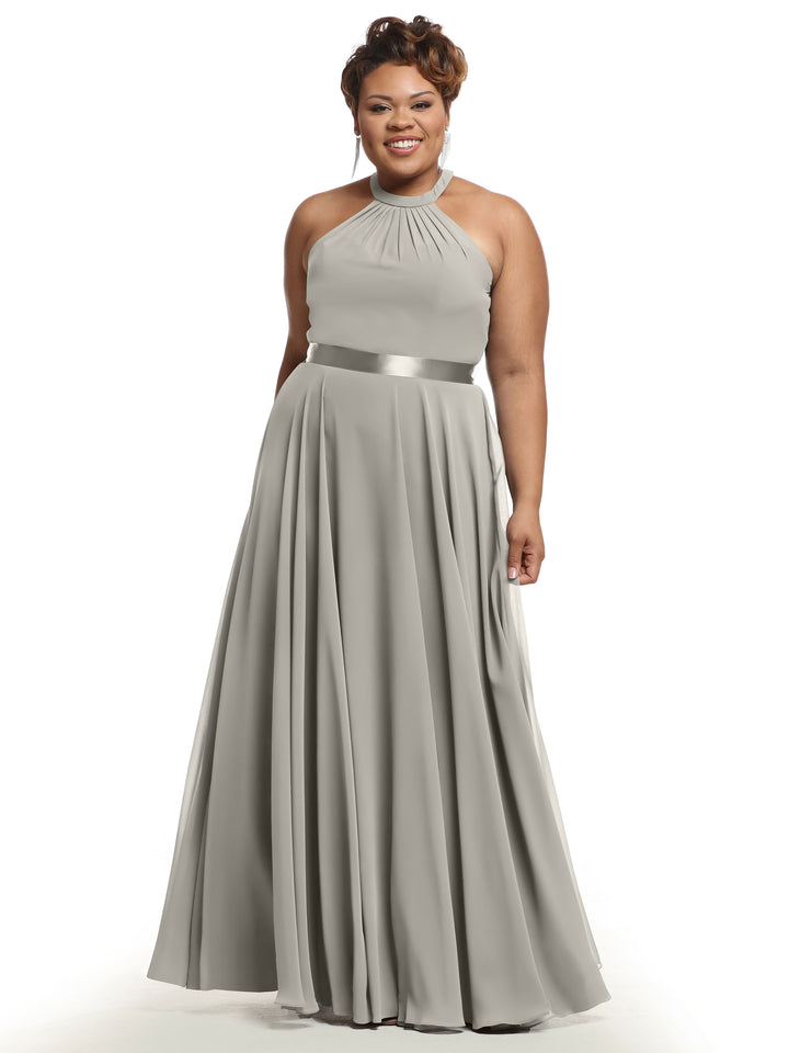 A woman in Avery Austin’s 80038: a sleeveless, floor-length A-line chiffon dress with a halter neckline and satin waistband, standing and smiling against a white background.
