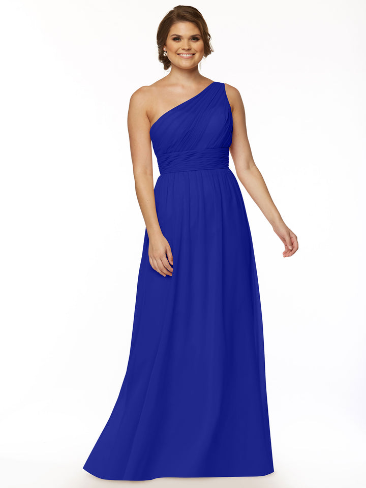A woman in Avery Austin’s 80047 cobalt one-shoulder chiffon dress with a ruched bodice stands smiling against a plain white background, embodying modern elegance.