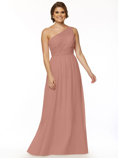 A woman stands smiling in the Avery Austin 80047—a sleeveless, dusty rose one-shoulder chiffon dress with a modern cutout and ruched bodice—set against a plain white background.