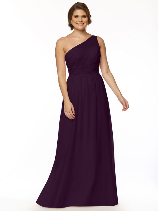 A woman wearing Avery Austin’s 80047, a floor-length deep purple one-shoulder chiffon dress with a ruched bodice, stands smiling against a plain white background.