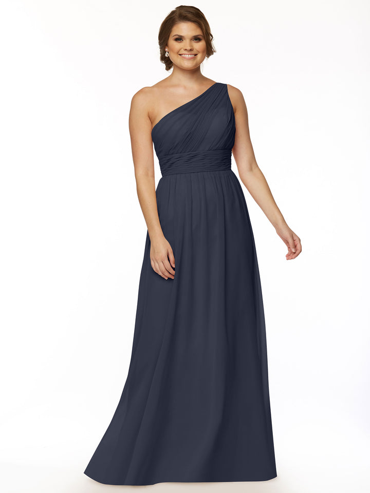 A woman smiles against a white background in Avery Austin’s 80047, a floor-length dark blue one-shoulder chiffon dress with a fitted ruched bodice and flowing skirt.