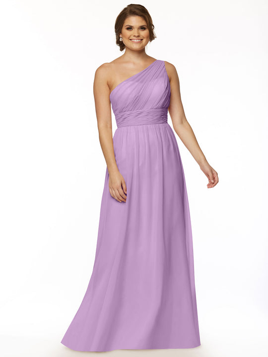A woman smiles against a white background, wearing Avery Austin’s style 80047: a long lavender one-shoulder chiffon dress with a fitted, ruched bodice.