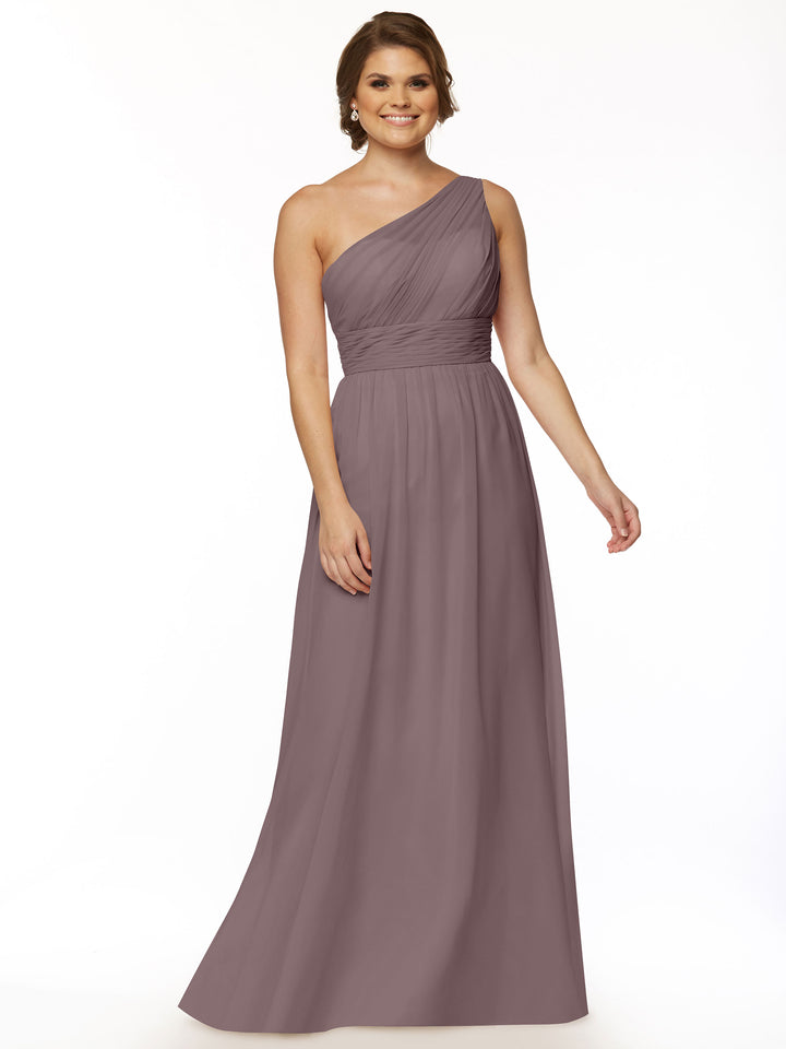 A woman smiles against a plain white background, wearing Avery Austin’s 80047—a modern one-shoulder chiffon dress with a fitted ruched bodice and flowing mauve skirt.