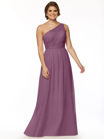 A woman with short brown hair and earrings poses against a white background in Avery Austin's 80047—a mauve, floor-length one-shoulder chiffon dress with a pleated bodice and flowing skirt that brings modern elegance to a classic style.