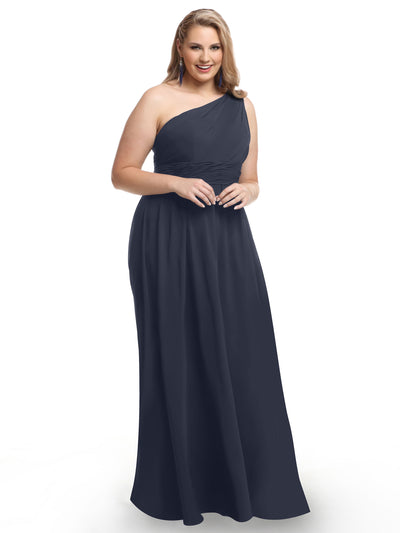 A woman smiles against a plain white background wearing Avery Austin style 80047, a floor-length, one-shoulder chiffon dress with a modern twist.