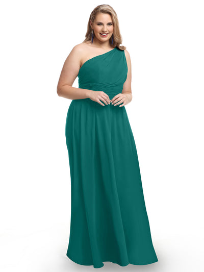 A woman stands smiling with her hands clasped, wearing Avery Austin’s 80047—a floor-length, teal one-shoulder chiffon dress—against a plain white background.