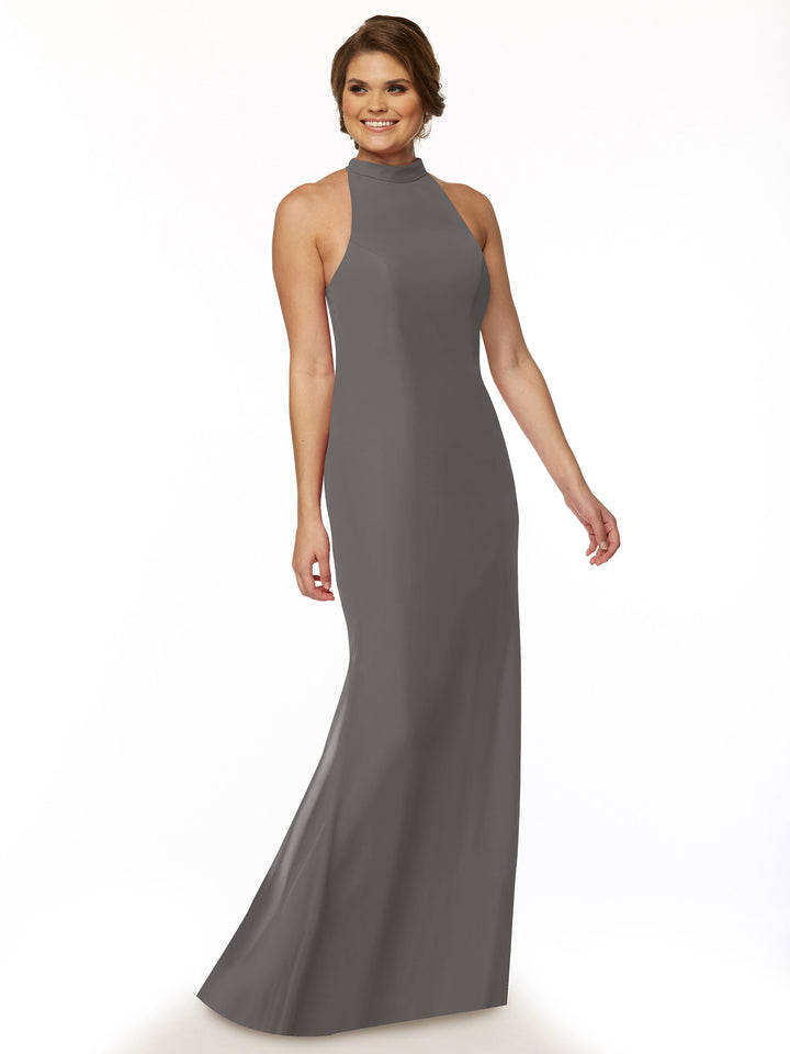A woman with short brown hair smiles while posing against a white background, wearing the Avery Austin 80068 sleeveless, high-neck, floor-length chiffon bridesmaid dress.