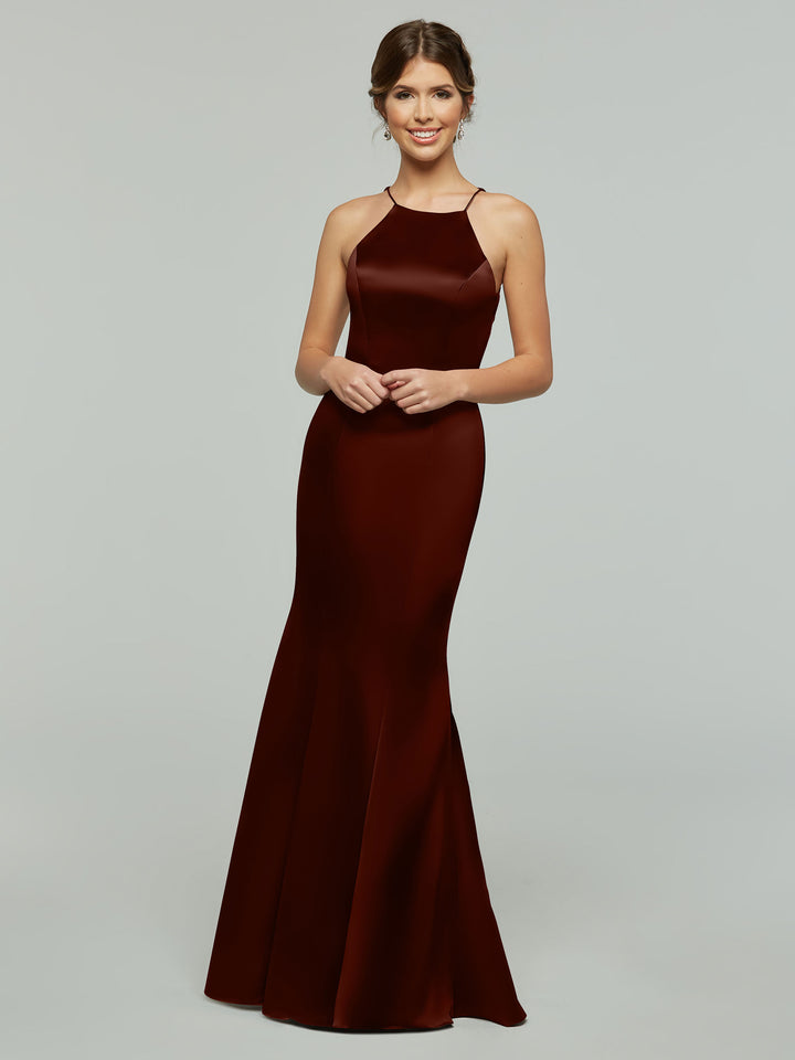 A woman smiles in Avery Austin’s 80071, a sleeveless, floor-length burgundy satin dress with a fitted bodice and halter neckline, standing against a plain light gray background.