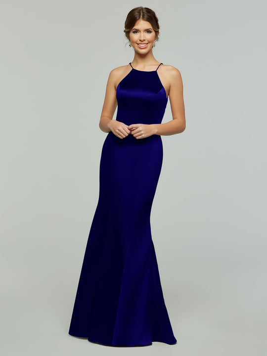 A woman smiles in Avery Austin’s 80071 dress—a sleeveless, floor-length royal blue gown with a halter neckline and flared skirt. Her hair is in an updo as she poses against a plain light gray background.