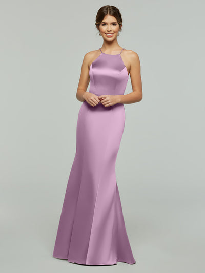 A smiling woman models Avery Austin's 80071 gown—a sleek, floor-length lavender dress with a fitted silhouette and halter neckline—posed against a plain light gray background.
