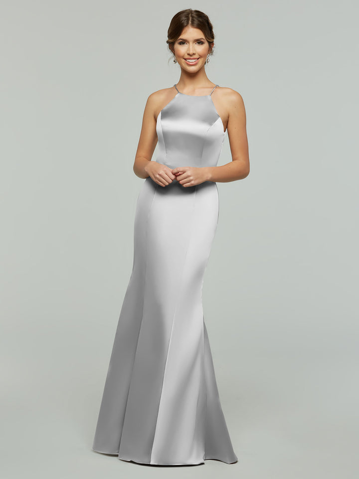 A woman wearing Avery Austin style 80071, a sleeveless floor-length silver satin halter gown, stands smiling with her hands clasped in front of her against a plain light gray background.