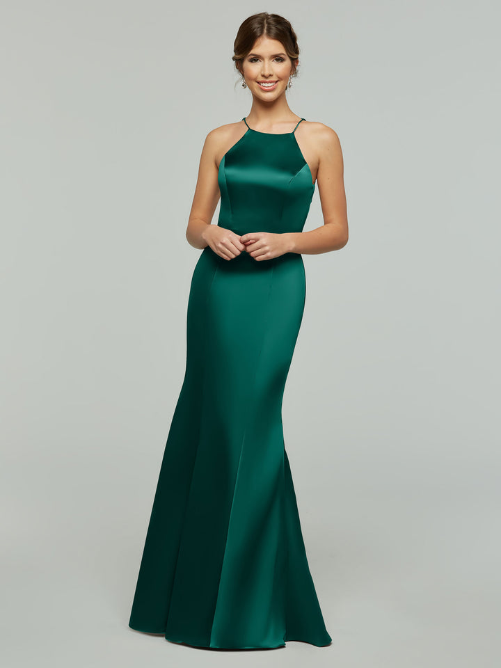 A woman stands smiling in Avery Austin’s 80071, a floor-length fitted dress with a flared hem and sleeveless halter neckline, shown against a plain light gray background.