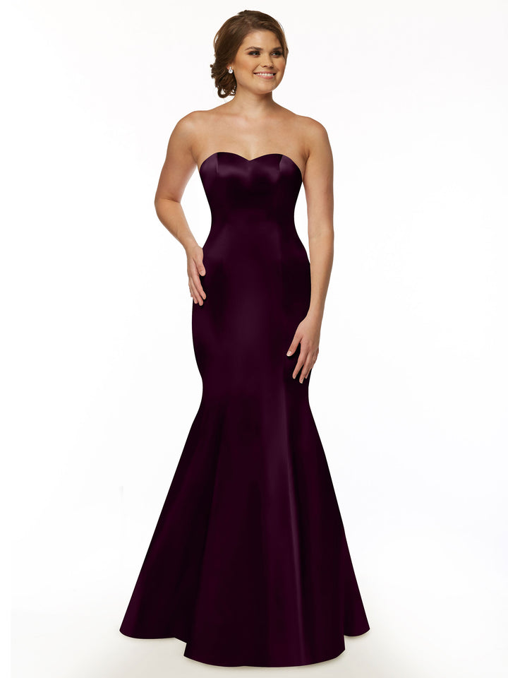 A woman smiles against a plain white background wearing the Avery Austin TH-80072 strapless satin mermaid bridesmaid dress in aubergine.