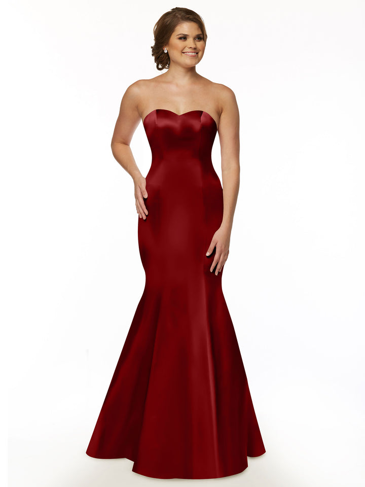 Smiling woman models Avery Austin’s 80072 dress in claret, featuring a strapless sweetheart neckline and floor-length fit and flare silhouette, with her hair styled back against a plain white background.