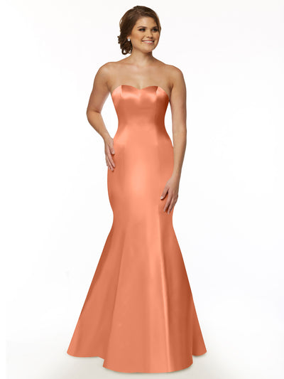 A woman smiles against a white background wearing Avery Austin’s 80072, a dark coral satin mermaid gown with a strapless sweetheart neckline and ruffled back.