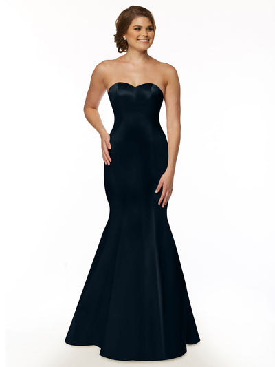 A woman with light skin and brown hair styled up smiles gently as she models Avery Austin's 80072—a strapless, form-fitting black bridesmaid dress with a mermaid silhouette—against a white background.
