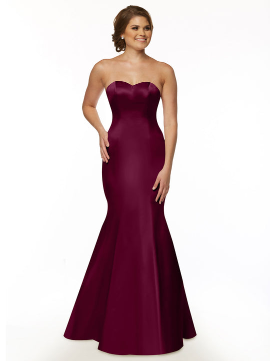 A woman wears the Avery Austin 80072 strapless satin mermaid bridesmaid dress in plum, elegantly flowing to the floor against a plain white background.