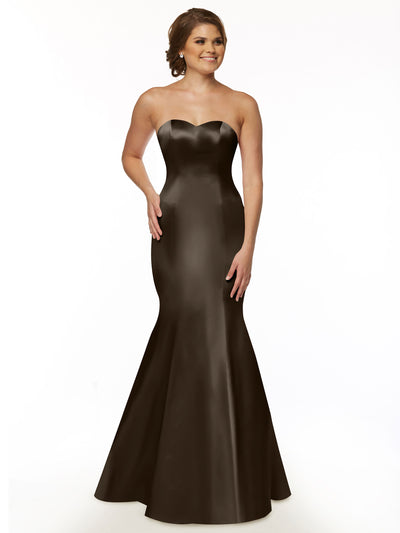 A woman models Avery Austin style 80072, a taupe strapless mermaid gown with sweetheart neckline and ruffled back, posing against a white background with one hand on her hip and the other by her side, smiling.