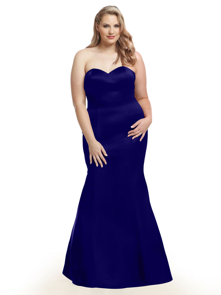 A woman stands facing forward against a white background wearing Avery Austin style 80072, a floor-length, strapless bridesmaid dress in cobalt satin.