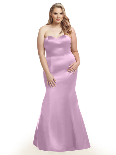 A woman with long, wavy blonde hair models Avery Austin’s 80072, a strapless, floor-length lilac fit and flare dress, standing forward with one hand on her hip against a white background.