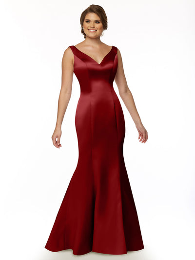 A woman smiles against a white background, wearing Avery Austin’s 80078—a sleeveless, deep red, floor-length fit and flare mermaid gown with a V-neckline and ruffled back.