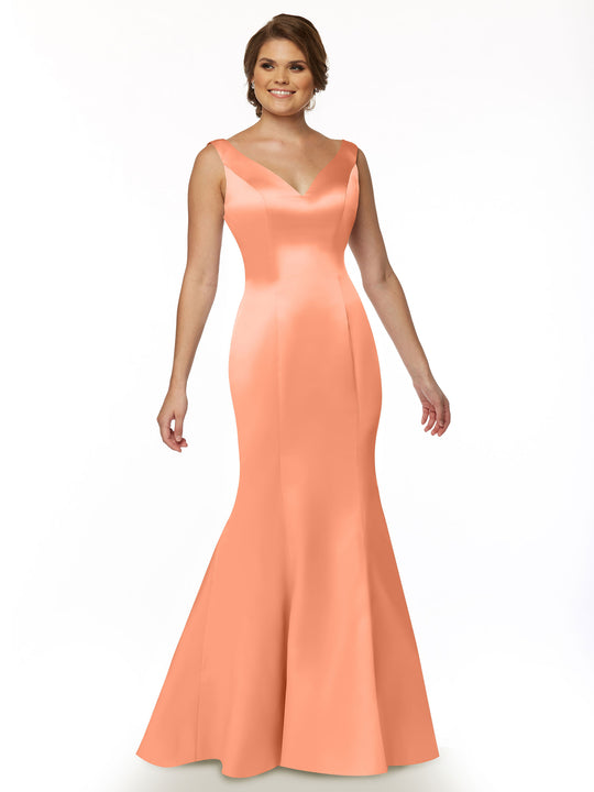 A woman in Avery Austin's 80078 mermaid gown, featuring a sleeveless peach satin design with a V-neckline and ruffled back, smiles against a plain white background.