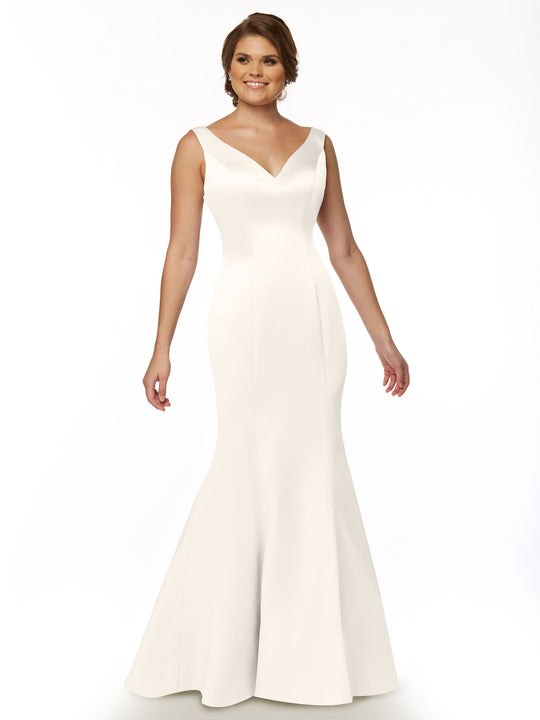 A woman models Avery Austin’s 80078, a sleeveless, floor-length white fit and flare mermaid gown with a V-neckline, standing against a plain white background and smiling gently.