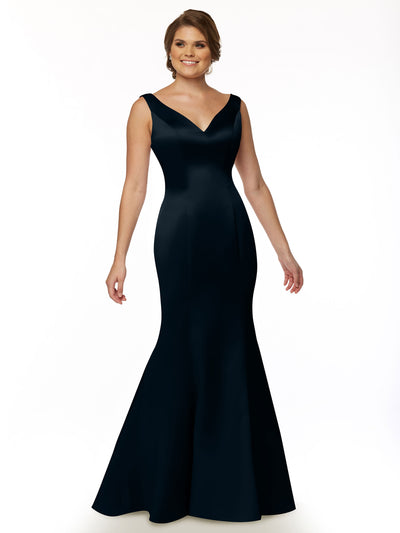 A woman smiles in Avery Austin’s 80078 evening gown, a sleeveless, floor-length navy dress with a V-neckline and fit-and-flare mermaid silhouette, set against a plain white background.