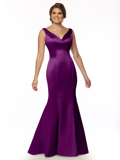 A woman in the Avery Austin 80078 sleeveless, deep purple satin V-neck gown with a fitted bodice and flared skirt stands against a white background, smiling with her hair in an elegant updo.