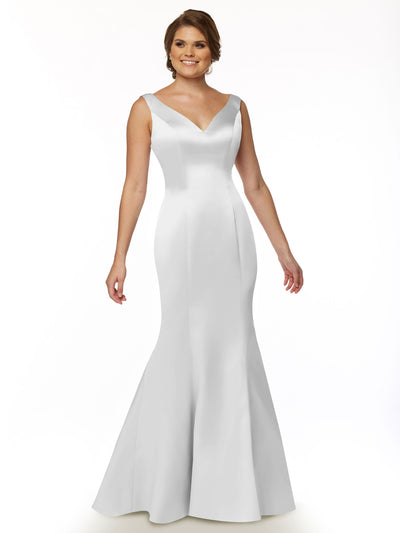 A woman wearing Avery Austin’s 80078, a sleeveless floor-length white satin fit and flare gown with a V-neckline and flared hem, stands smiling against a plain white background.