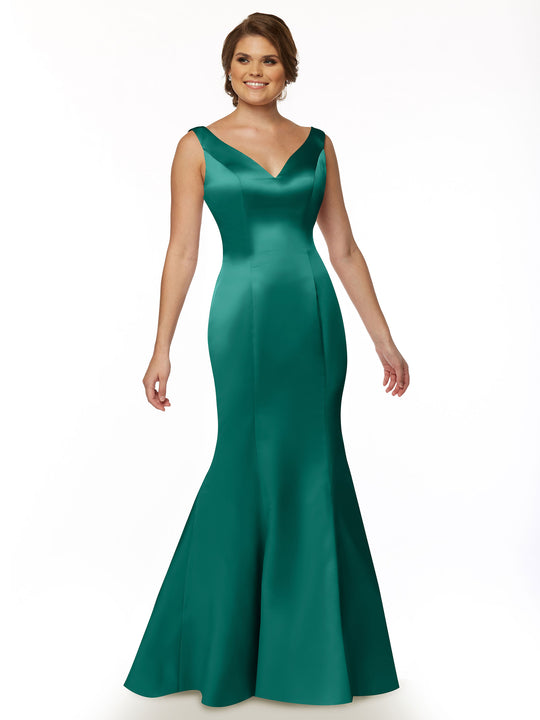 A woman stands against a white background, smiling with her hair styled up, wearing Avery Austin’s 80078—a fitted emerald green satin fit and flare gown with a sleeveless V-neckline and flared, floor-length skirt.