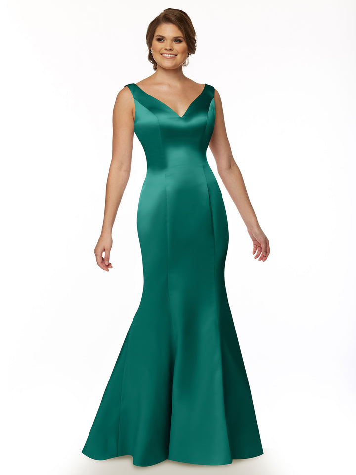 A woman stands against a white background, smiling with her hair styled up, wearing Avery Austin’s 80078—a fitted emerald green satin fit and flare gown with a sleeveless V-neckline and flared, floor-length skirt.