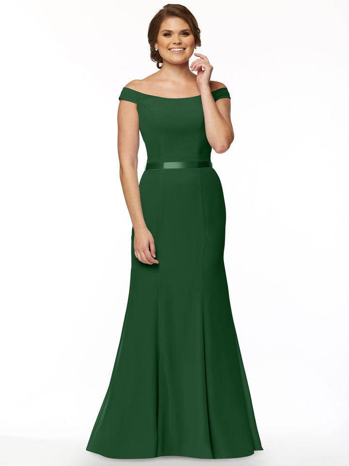A woman with a neat short brown hairstyle smiles against a white background, modeling Avery Austin style 80079—an off-the-shoulder dark green bridesmaid dress featuring a fitted bodice and flared skirt.