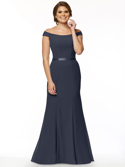 A woman smiles in Avery Austin’s 80079—an elegant navy blue off-the-shoulder bridesmaid dress with a fitted bodice and flared skirt—against a plain white background.