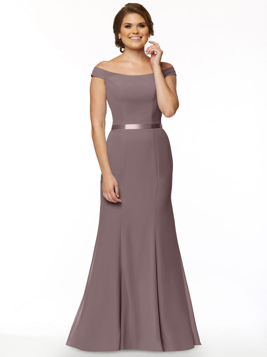 A woman poses gracefully in the Avery Austin 80079 mauve off-the-shoulder bridesmaid dress with a satin waistband and fit-and-flare silhouette, smiling with her hair up against a plain white background.