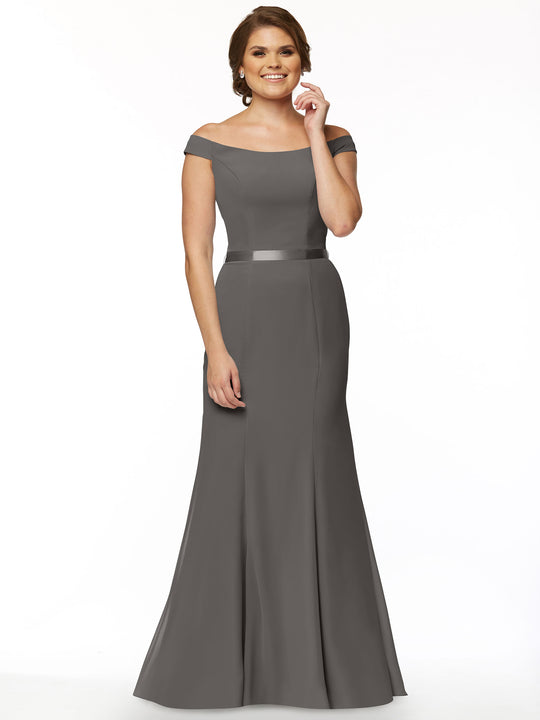 A woman models Avery Austin’s 80079: an off-the-shoulder, floor-length gray chiffon bridesmaid dress with a satin waistband. She smiles in an updo against a plain white background.
