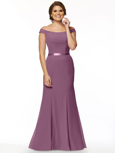 A woman in Avery Austin’s 80079, an off-the-shoulder floor-length mauve bridesmaid dress with a satin waistband, smiles against a plain white background.