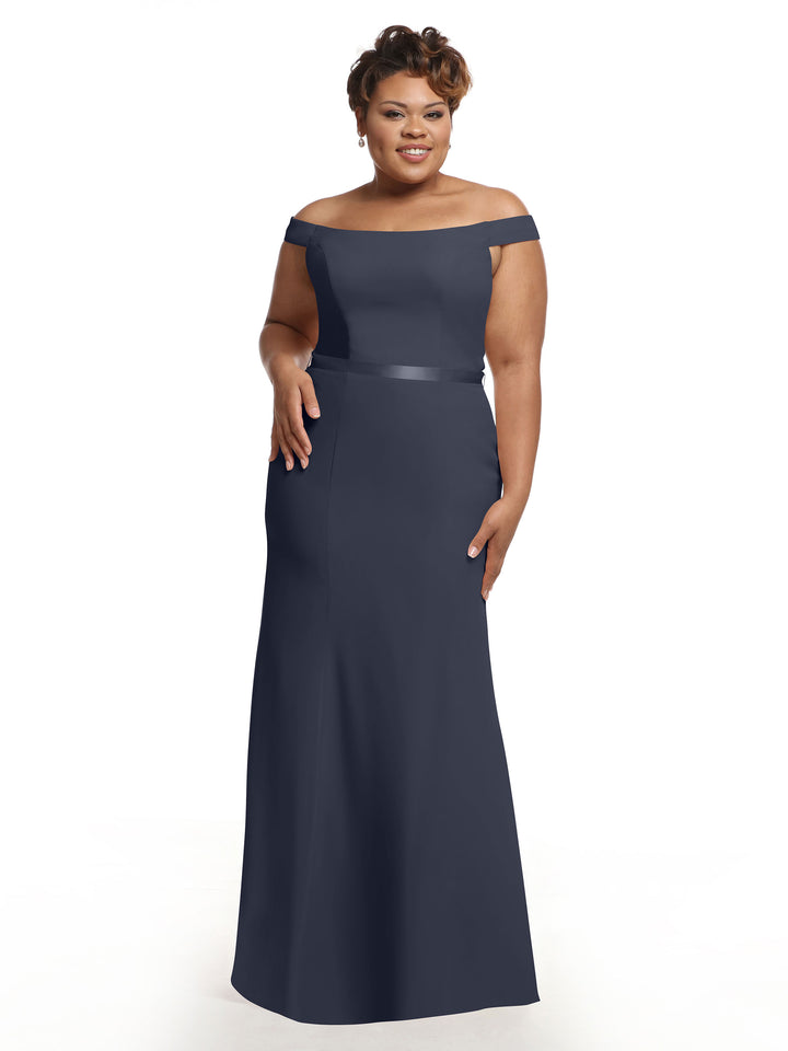 A woman models the Avery Austin 80079 off-the-shoulder bridesmaid dress in navy blue, posing against a white background with a slight smile, one hand at her side and the other on her hip.