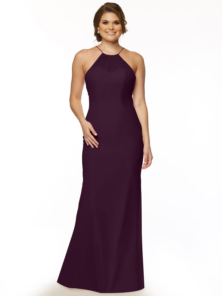 A woman smiles against a white background wearing Avery Austin’s 80083, a sleeveless aubergine chiffon halter gown with a keyhole back. Her hair is in loose waves and she rests one hand on her hip.