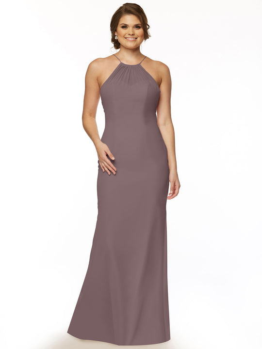 A woman smiles in the Avery Austin 80083 dress—a sleeveless, floor-length mauve halter gown with a high neckline. She wears earrings and a ring, has her hair styled up, and poses against a plain white background.