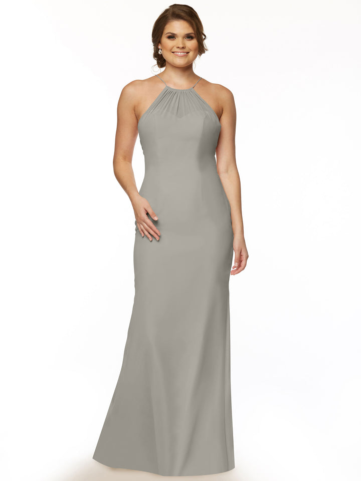 A woman smiles in the Avery Austin 80083—a long, light gray chiffon halter dress with a keyhole back. She wears her hair styled back and minimal jewelry, standing against a plain white background.